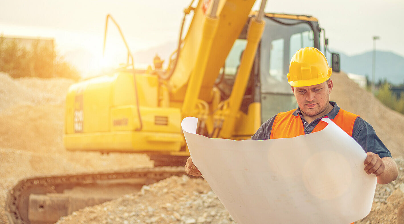 Capo cantiere con escavatore sullo sfondo